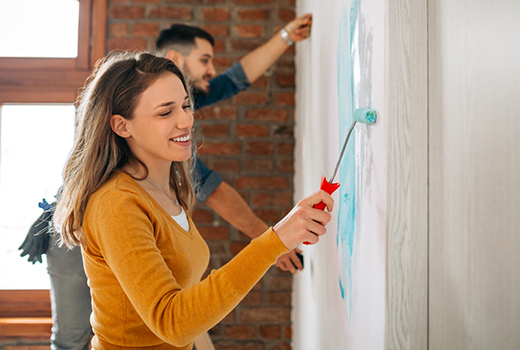 Junges Paar-Mann und Frau wählen Farbe für das Innere zu Hause und streichen Wände in blauer Farbe.